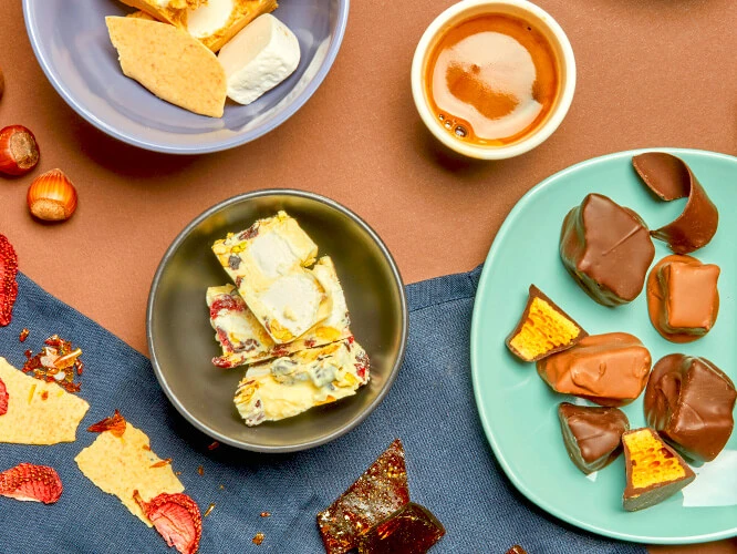 Handmade chocolates on a table, including White Rocky Road, Chocolate coated Honeycomb, caramel, and hot chocolate.