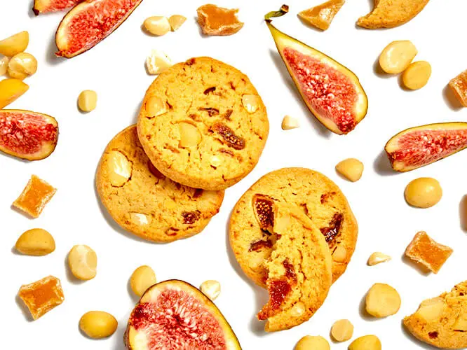 Cookies surrounded by ingredients including figs, macadamia nuts and ginger.