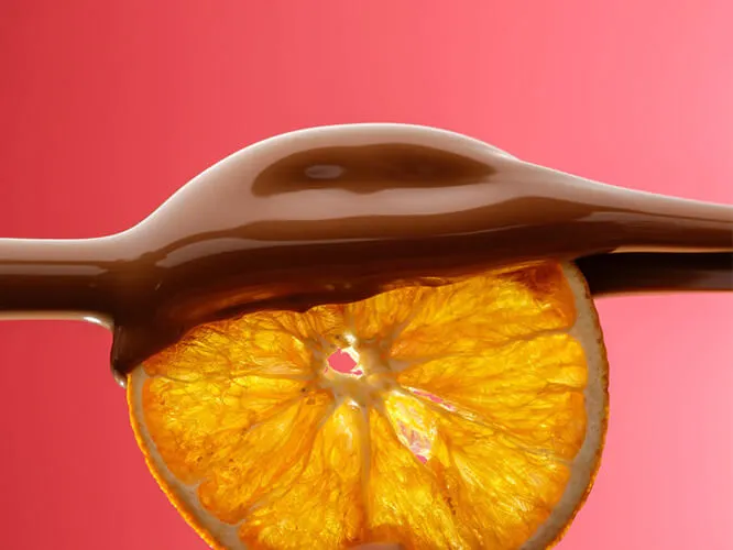 Dried orange slice being coated in Belgian chocolate.