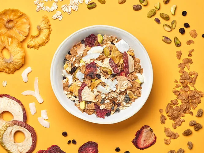 Gourmet Muesli - a bowl of Summer Muesli surrounded by ingredients such as pineapple, strawberry, apple, pistachio and coconut.