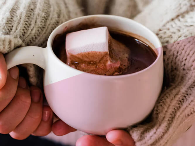 A mug of hot chocolate being held in hands.